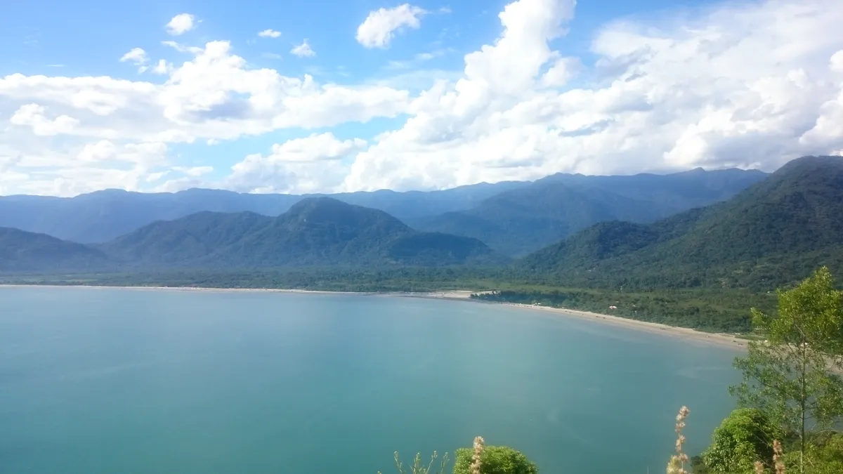 Vista panorâmica da Praia da Almada em Ubatuba com serra ao fundo e mar calmo